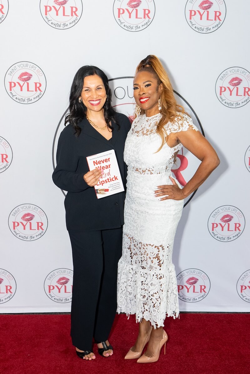 Karmetria with guest smiling at Paint Your Lips Red Event with Never Wear Red Lipstick book